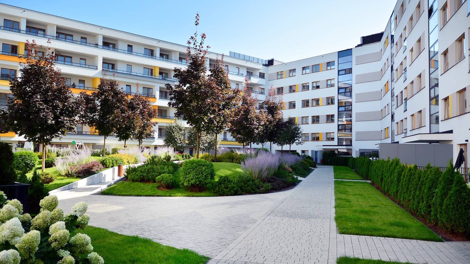 Apartment complex exterior with vibrant landscaping & plantings